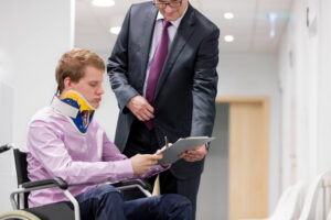 Injured employee on wheelchair submitting workers compensation claim form to lawyer.