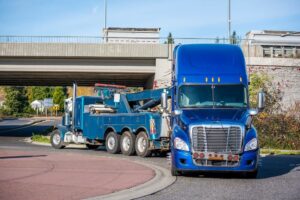 Blue tractor truck passing under the bridge.