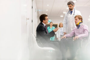 Injured on wheelchair talking with his doctor and lawyer for personal injury lawsuit.