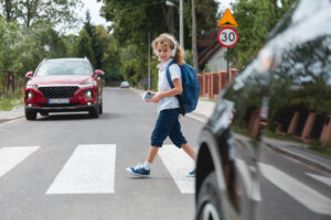 Boy wearing headphones crossing the street.