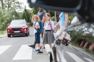 Driver in the car stops while school kids are crossing.