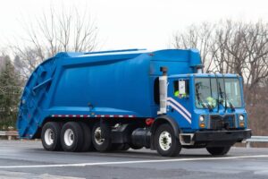 Blue garbage truck vehicle trash passing.
