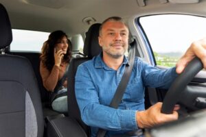 Uber passenger talking on cellphone, sitting on backseat.