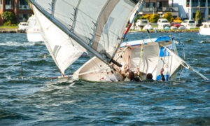 White sailboat sinking due to engine malfunction.